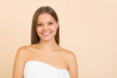 Bej arka planda, uzun dalgalı saçları olan güzel bir genç kadın.