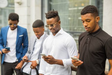 Yazın binanın yanında ellerinde telefonlarla dört Afrikalı genç adam.
