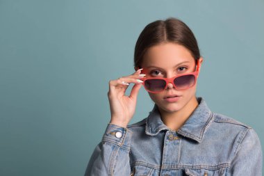 portrait of a beautiful young woman in sunglasses on a blue background