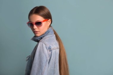 portrait of a beautiful young woman in sunglasses on a blue background