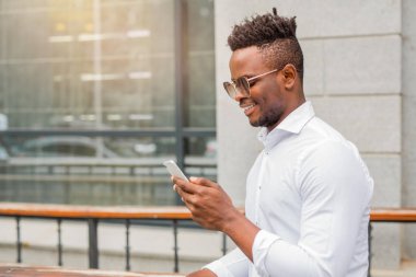 handsome young african man in a white shirt with a phone in his hand