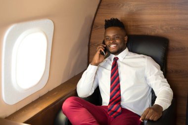 Beyaz gömlekli yakışıklı afrikalı adam uçak koltuğunda