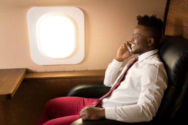 Beyaz gömlekli yakışıklı afrikalı adam uçak koltuğunda