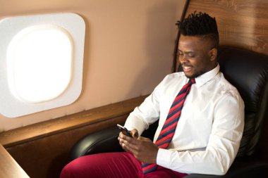 Beyaz gömlekli yakışıklı afrikalı adam uçak koltuğunda