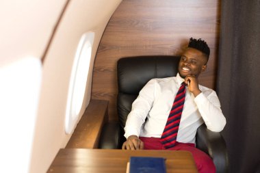 Beyaz gömlekli yakışıklı afrikalı adam uçak koltuğunda