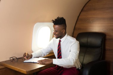 Beyaz gömlekli yakışıklı afrikalı adam uçak koltuğunda