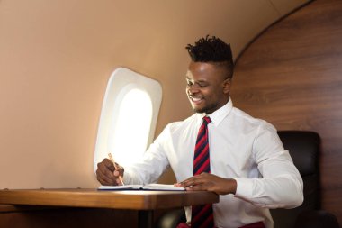 Beyaz gömlekli yakışıklı afrikalı adam uçak koltuğunda