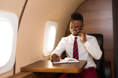 Beyaz gömlekli yakışıklı afrikalı adam uçak koltuğunda