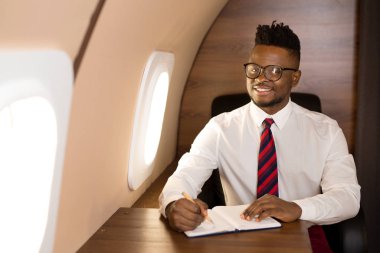 Beyaz gömlekli yakışıklı afrikalı adam uçak koltuğunda