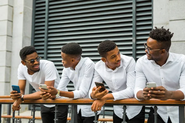 Cuatro Hombres Africanos Jóvenes Guapos Camisas Blancas Con Teléfonos Sus —  Fotos de Stock