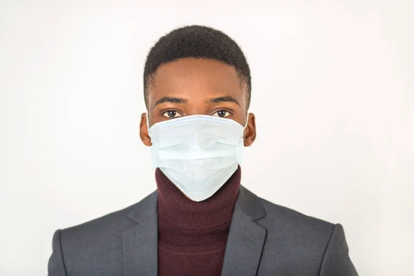 young african man in antivirus gauze mask on his face on a white background