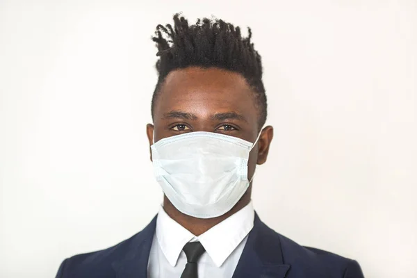 Beyaz bir arka planda, yüzünde antivirüs gazlı bez maskesi olan Afrikalı genç bir adam.