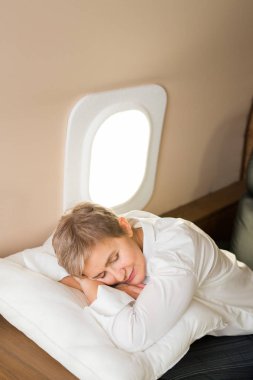 Güzel, şık bir kadın. Yastığın üzerinde özel bir jet kabininde uyuyor.
