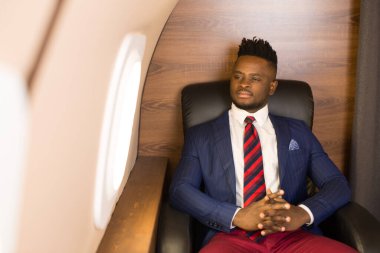 Özel jet kabininde takım elbiseli yakışıklı Afrikalı genç adam.