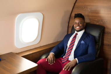 Özel jet kabininde takım elbiseli yakışıklı Afrikalı genç adam.