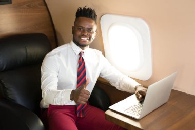 Özel jet kabininde beyaz gömlekli yakışıklı Afrikalı genç bir adam.