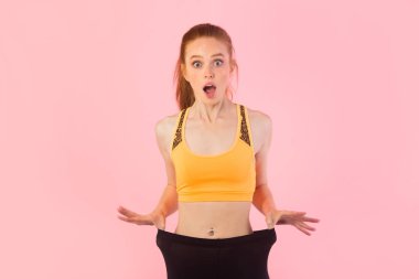 Pembe arka planda kırmızı saçlı güzel, zayıf bir kadın.