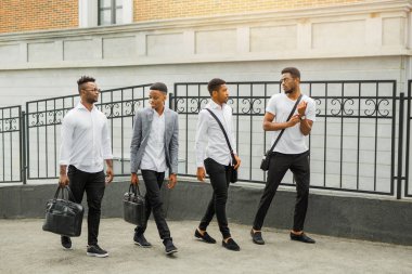 Yazın açık havada beyaz gömlekli dört Afrikalı genç adam.