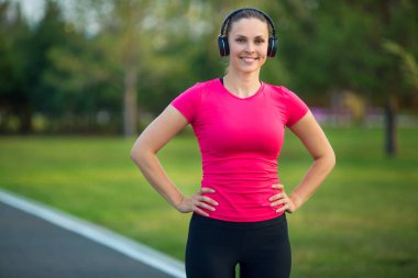 Güzel genç bir kadın yaz parkında koşu bandında koşuyor.