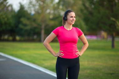 Güzel genç bir kadın yaz parkında koşu bandında koşuyor.
