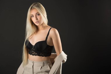 Siyah arka planda takım elbiseli güzel genç bir kadın.