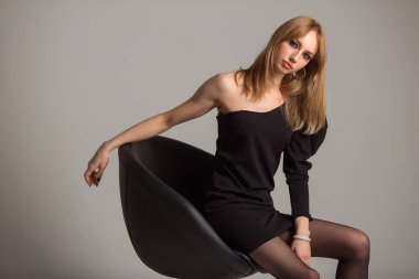  Gri arka planda siyah elbiseli güzel bir kadın.