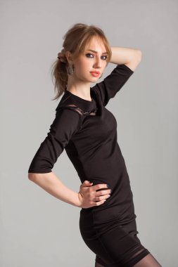 Gri arka planda siyah elbiseli güzel bir kadın.