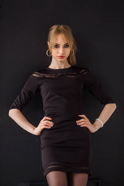 beautiful young woman with makeup in a black dress on a black background