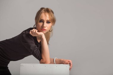 Gri arka planda siyah elbiseli güzel bir kadın.