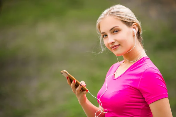beautiful young woman in a sports pink t-shirt with a phone in the river
