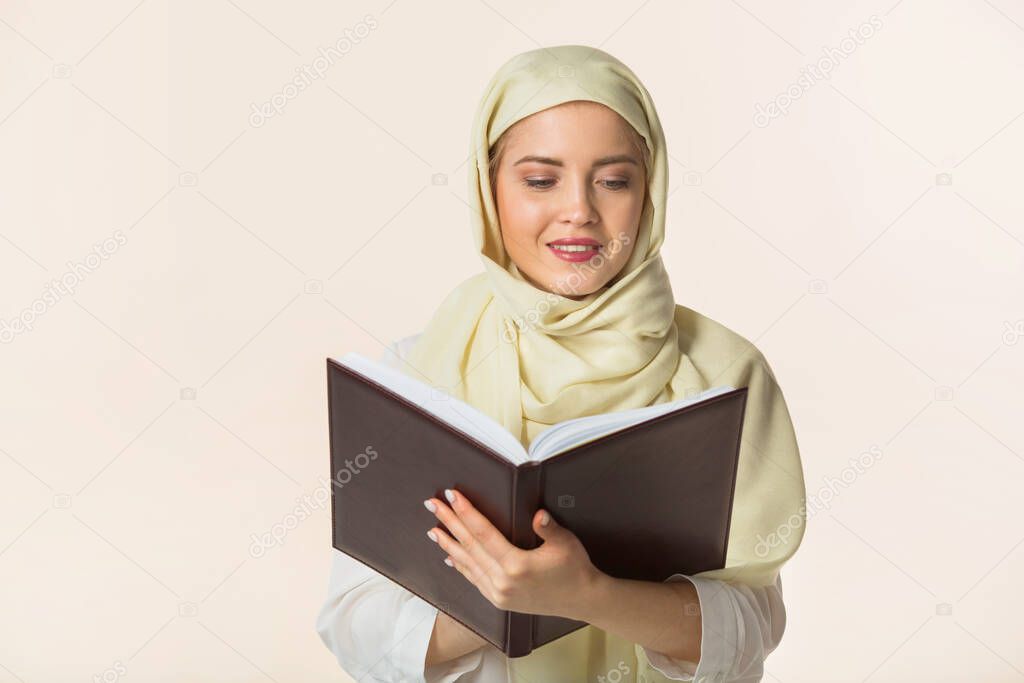 beautiful young woman in a muslim shawl with a book in her hands