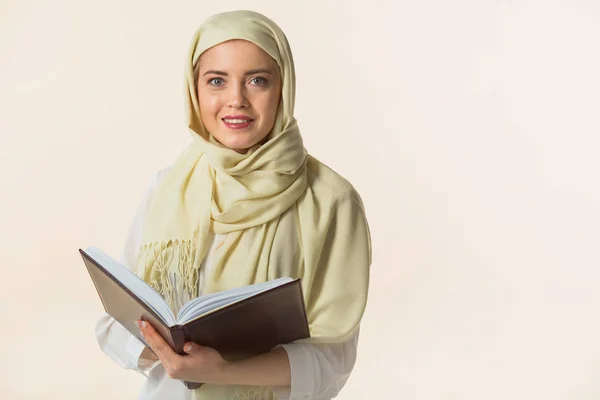 一个穿着穆斯林披肩 手里拿着一本书的漂亮的年轻女人 — 图库照片