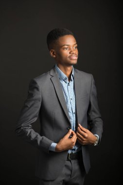Siyah arka planda takım elbiseli yakışıklı bir Afrikalı.