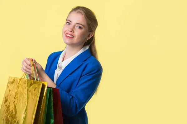 Bela Jovem Mulher Uma Jaqueta Azul Fundo Amarelo Com Pacotes — Fotografia de Stock