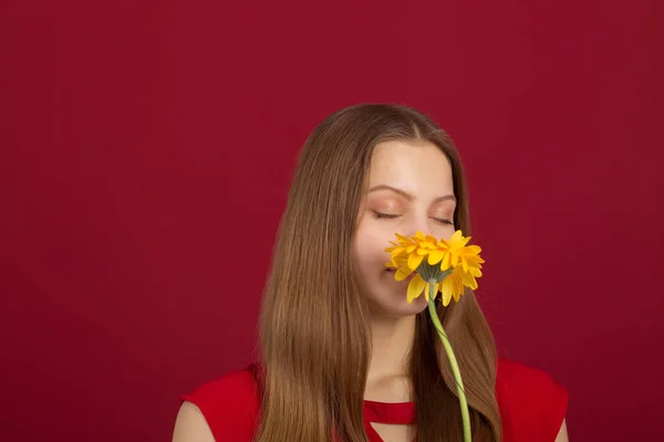 赤い背景に花を手にした美しい若い女性が — ストック写真