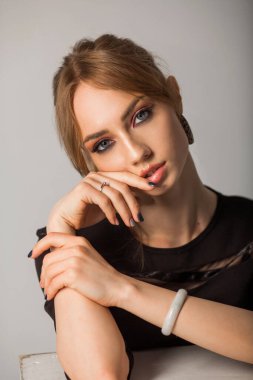 Gri arka planda siyah elbiseli güzel bir kadın.