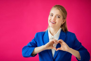 Pembe arka planda mavi ceketli güzel bir kadın.