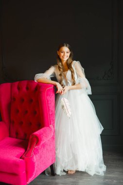 Siyah arka planda beyaz elbiseli güzel bir kadının portresi.