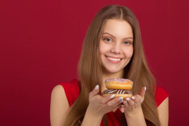  Saçları kırmızı arka planda donutlu güzel bir genç kadın.