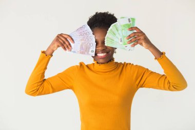 Beyaz arka planda, elinde avroyla güzel, genç bir Afrikalı kadın.