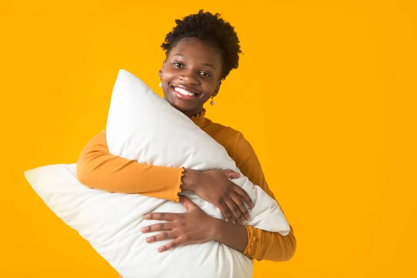 beautiful young african woman on a yellow background with a pillow
