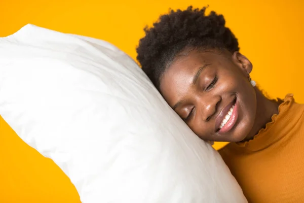 beautiful young african woman on a yellow background with a pillow