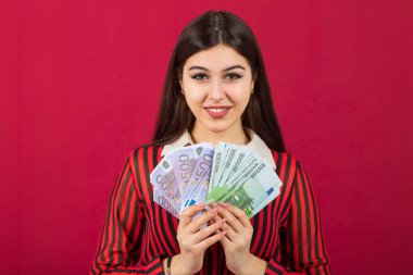 Avrosu avucunun içinde, kırmızı bir arka planı olan güzel genç bir kadın.