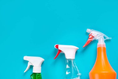 Mavi arka planda temizleyici maddesi olan üç sprey şişe.