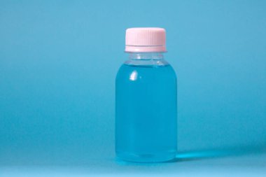 Mavi arka planda antiseptik olan plastik şişe.