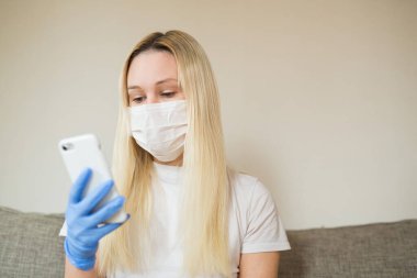  Elinde telefonla tıbbi maske takan güzel bir kadın.