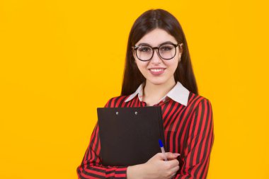 Sarı bir arka planda elinde klasörle güzel bir genç kadın.