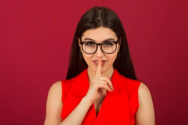 Kırmızı arka planda kırmızı takım elbiseli güzel bir kadın.