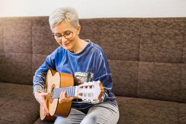 Gitar çalan şık bir yetişkin kadın.