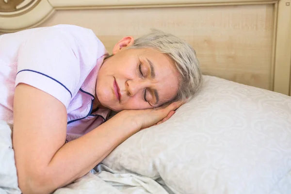 elderly woman on bed in bed under the covers